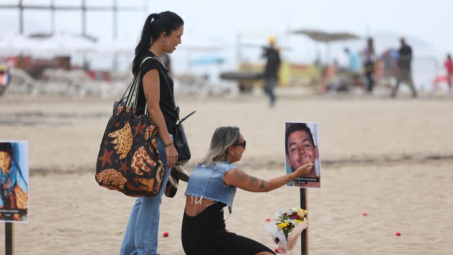 Seorang wanita berlari melewati 48 gambar anak-anak yang ditembak mati selama operasi polisi selama pemerintahan gubernur Rio de Janeiro Claudio Castro, oleh LSM Rio de Paz, di pantai Copacabana di Rio de Janeiro, Brasil, 18 Desember 2024. (REUTERS/Pilar Olivares)