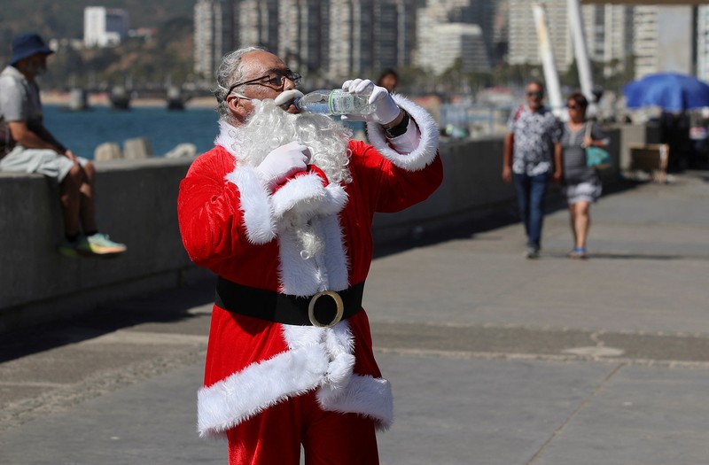 Seorang wanita melindungi putranya dari terik matahari dengan tas kardus saat gelombang panas melanda negara itu, di Vina del Mar, Cile, 19 Desember 2024. (REUTERS/Rodrigo Garrido)