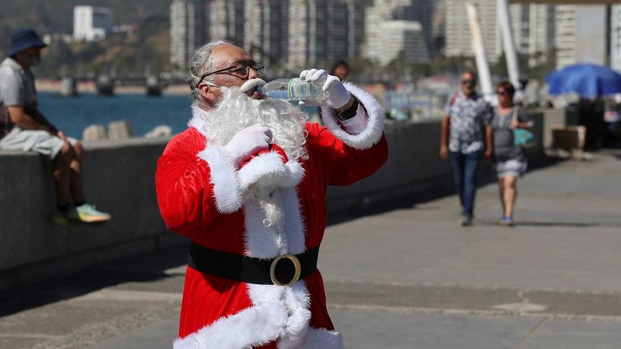 Seorang pria berpakaian Sinterklas menyejukkan diri dengan air saat gelombang panas melanda negara itu, di Vina del Mar, Cile, 19 Desember 2024. (REUTERS/Rodrigo Garrido)