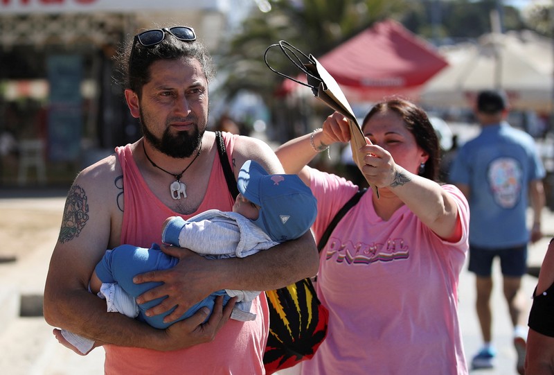 Seorang wanita melindungi putranya dari terik matahari dengan tas kardus saat gelombang panas melanda negara itu, di Vina del Mar, Cile, 19 Desember 2024. (REUTERS/Rodrigo Garrido)