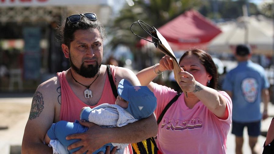 Seorang wanita melindungi putranya dari terik matahari dengan tas kardus saat gelombang panas melanda negara itu, di Vina del Mar, Cile, 19 Desember 2024. (REUTERS/Rodrigo Garrido)