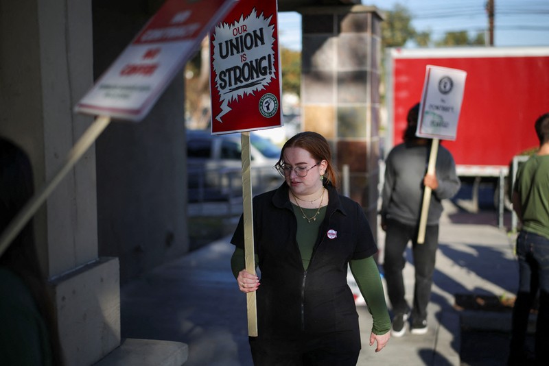 Baristas hold signs as they picket in front of a Starbucks in Burbank, California, U.S., December 20, 2024. REUTERS/Daniel Cole