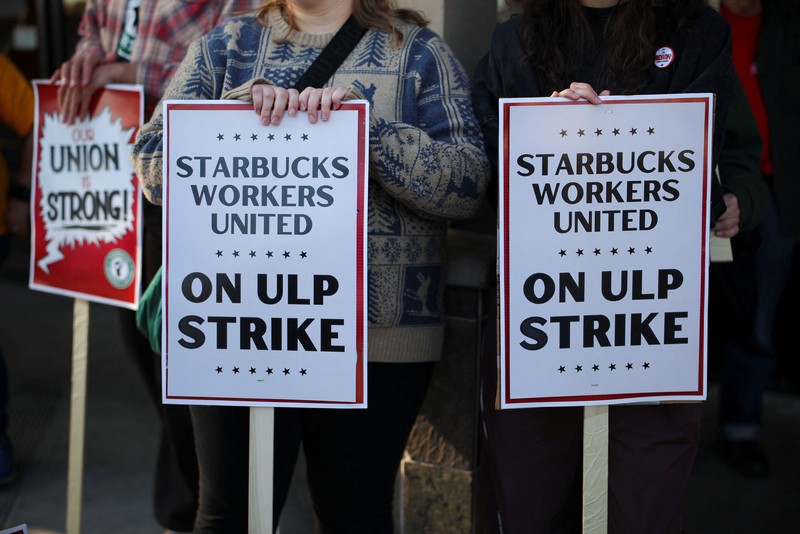Baristas hold signs as they picket in front of a Starbucks in Burbank, California, U.S., December 20, 2024. REUTERS/Daniel Cole