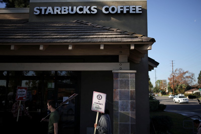 STARBUCKS-LABOR/ Baristas hold signs as they picket in front of a Starbucks in Burbank, California, U.S., December 20, 2024. REUTERS/Daniel Cole
