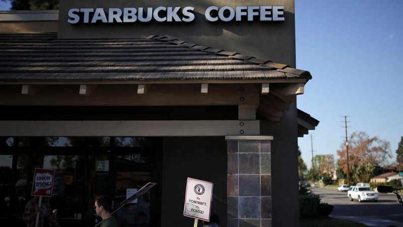 Baristas hold signs as they picket in front of a Starbucks in Burbank, California, U.S., December 20, 2024. REUTERS/Daniel Cole