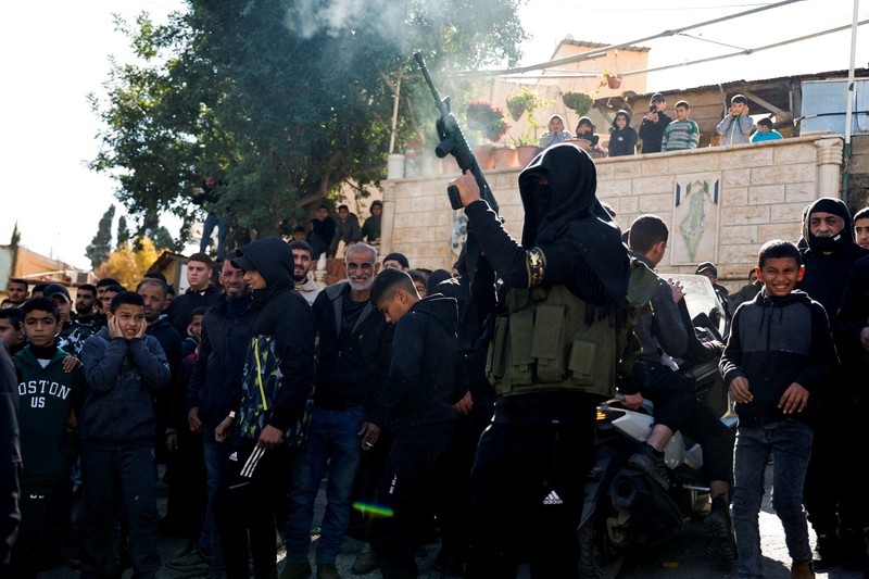 ISRAEL-PALESTINIANS/WEST BANK-STRIKE-FUNERAL A gunman fires a rifle during the funeral of Rayan Bani Odeh, a Palestinian child who was killed in an Israeli airstrike, in Tammoun, near Tubas, in the Israeli-occupied West Bank, December 25, 2024. REUTERS/Raneen Sawafta TPX IMAGES OF THE DAY