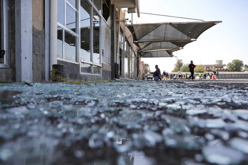 Orang-orang berjalan di dekat bangunan yang rusak di Bandara Sanaa, setelah serangan udara Israel di Sanaa, Yaman, 27 Desember 2024. (REUTERS/Khaled Abdullah)