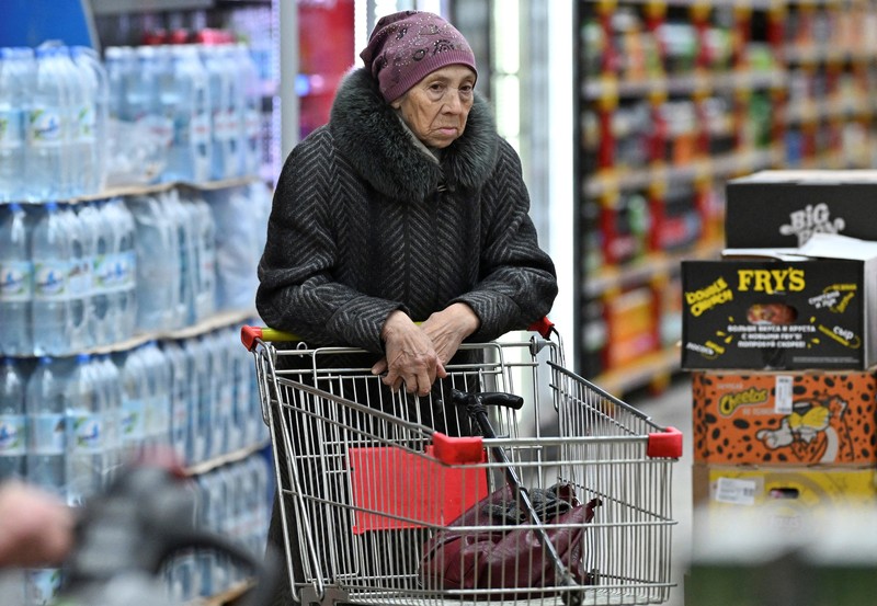 Seorang pelanggan berdiri di depan rak berisi bahan makanan di sebuah toko kelontong di kota Omsk, Siberia, Rusia, 13 Desember 2024. (REUTERS/Alexey Malgavko)