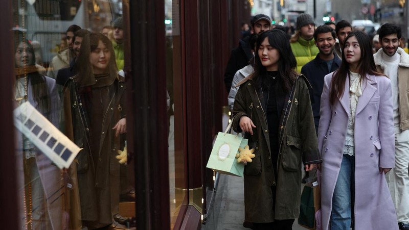 Seorang wanita menyeberang jalan dengan tas belanja di Regent St selama penjualan Boxing Day, di London, Inggris, 26 Desember 2024. (REUTERS/Jaimi Joy)