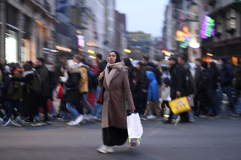 Seorang wanita menyeberang jalan dengan tas belanja di Regent St selama penjualan Boxing Day, di London, Inggris, 26 Desember 2024. Seorang wanita menyeberang jalan dengan tas belanja di Regent St selama penjualan Boxing Day, di London, Inggris, 26 Desember 2024. (REUTERS/Jaimi Joy)