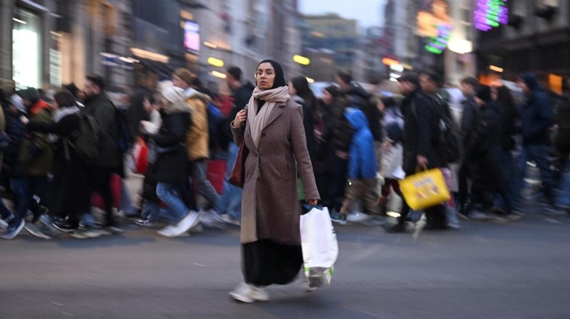 Seorang wanita menyeberang jalan dengan tas belanja di Regent St selama penjualan Boxing Day, di London, Inggris, 26 Desember 2024. (REUTERS/Jaimi Joy)