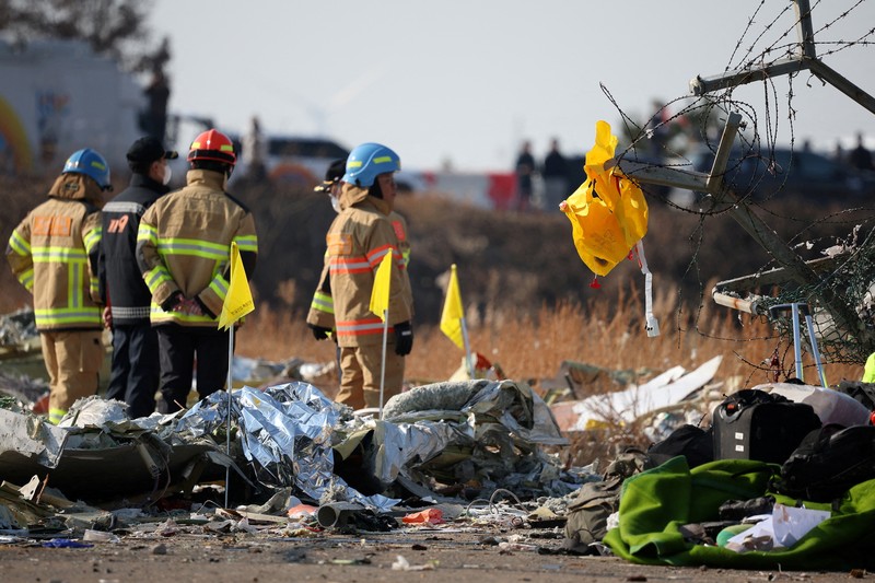 Petugas pemadam kebakaran membawa jenazah penumpang dari reruntuhan pesawat yang jatuh setelah keluar landasan di Bandara Internasional Muan, di Muan, Korea Selatan, 29 Desember 2024. (REUTERS/Kim Hong-Ji)