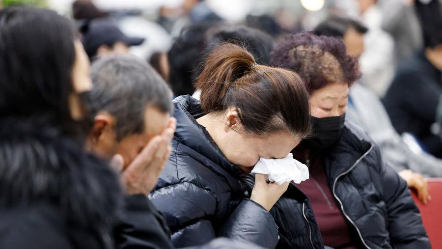 Orang-orang mendengarkan saat seorang pejabat mengungkapkan nama-nama tambahan penumpang yang tewas dalam kecelakaan pesawat di Bandara Internasional Muan, di Muan, Korea Selatan, 29 Desember 2024. (REUTERS/Kim Soo-hyeon)