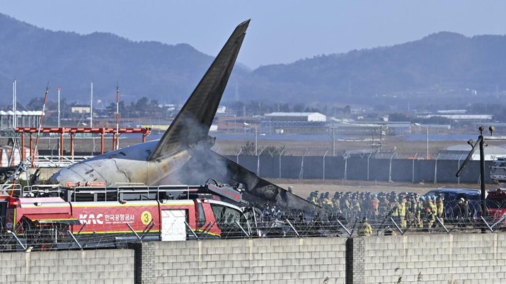 Petugas pemadam kebakaran dan anggota tim penyelamat bekerja di landasan pacu Bandara Internasional Muan di Muan, Korea Selatan, Minggu, 29 Desember 2024. (Lee Young-ju/Newsis via AP)