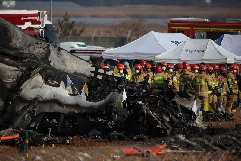 Petugas pemadam kebakaran membawa jenazah penumpang dari reruntuhan pesawat yang jatuh setelah keluar landasan di Bandara Internasional Muan, di Muan, Korea Selatan, 29 Desember 2024. (REUTERS/Kim Hong-Ji)