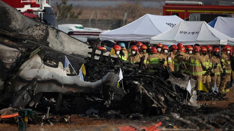 Petugas pemadam kebakaran membawa jenazah penumpang dari reruntuhan pesawat yang jatuh setelah keluar landasan di Bandara Internasional Muan, di Muan, Korea Selatan, 29 Desember 2024. (REUTERS/Kim Hong-Ji)