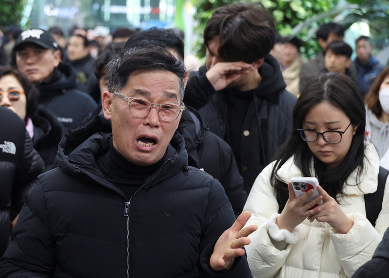 Orang-orang mendengarkan saat seorang pejabat mengungkapkan nama-nama tambahan penumpang yang tewas dalam kecelakaan pesawat di Bandara Internasional Muan, di Muan, Korea Selatan, 29 Desember 2024. (REUTERS/Kim Soo-hyeon)