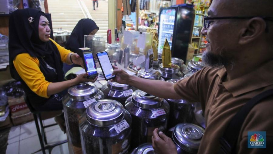 Pembeli memindai kode batang pembayaran Quick Response Code Indonesian Standard (QRIS) saat melakukan transaksi di Pasar Santa, Jakarta, Senin (30/12/2024). (CNBC Indonesia/Faisal Rahman)