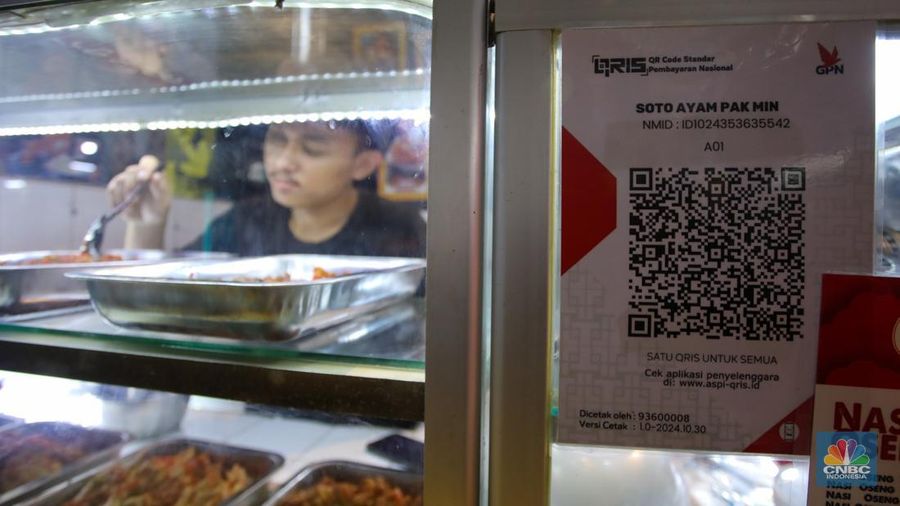 Pembeli memindai kode batang pembayaran Quick Response Code Indonesian Standard (QRIS) saat melakukan transaksi di Pasar Santa, Jakarta, Senin (30/12/2024). (CNBC Indonesia/Faisal Rahman)