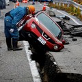 A worker looks at a car stuck on a broken road in the aftermath of an earthquake, near Anamizu, Japan, January 3, 2024. REUTERS/Kim Kyung-Hoon