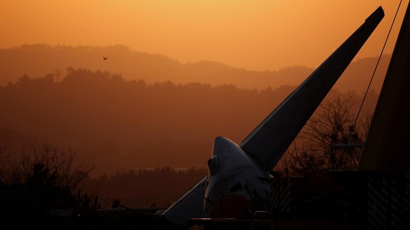 A bird flies by as the sun rises behind the aircraft that crashed after it went off the runway, at Muan International Airport, in Muan, South Korea, December 31, 2024. REUTERS/Kim Hong-Ji