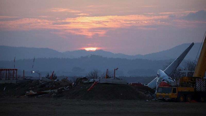 A bird flies by as the sun rises behind the aircraft that crashed after it went off the runway, at Muan International Airport, in Muan, South Korea, December 31, 2024. REUTERS/Kim Hong-Ji