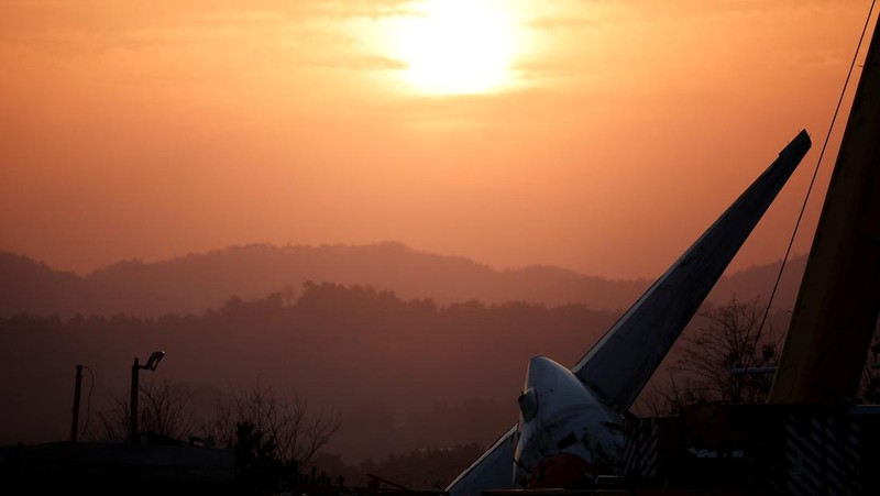 A bird flies by as the sun rises behind the aircraft that crashed after it went off the runway, at Muan International Airport, in Muan, South Korea, December 31, 2024. REUTERS/Kim Hong-Ji