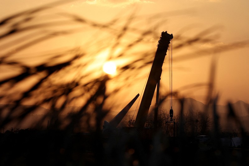 SOUTHKOREA-CRASH/ A bird flies by as the sun rises behind the aircraft that crashed after it went off the runway, at Muan International Airport, in Muan, South Korea, December 31, 2024. REUTERS/Kim Hong-Ji