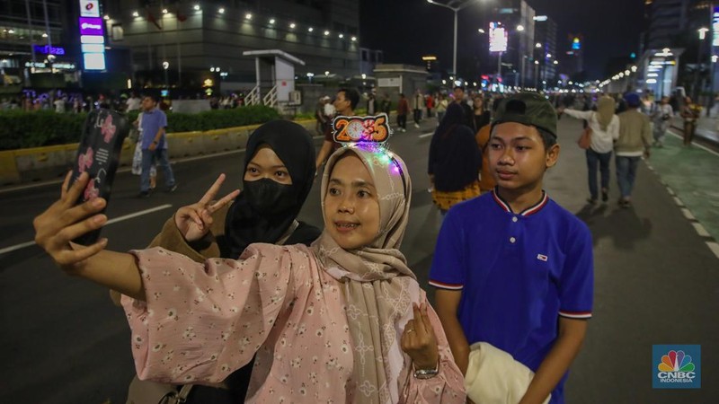 Warga memadati kawasan Bundaran Hotel Indonesia (HI) jelang malam pergantian tahun baru di Jakarta, Selasa (31/12/2024). (CNBC Indonesia/Faisal Rahman)