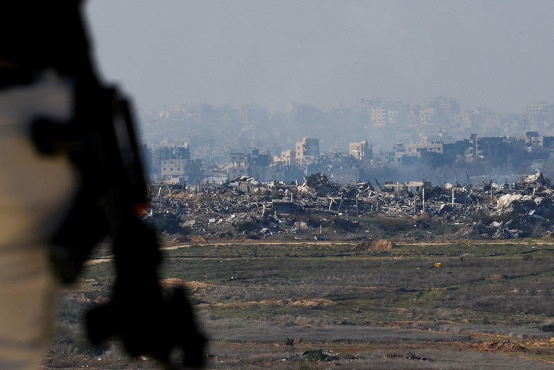 Seorang pria Yahudi Ultra-Ortodoks menyeka wajahnya, dengan latar belakang Gaza utara saat militer Israel melakukan operasi di dalam Jalur Gaza, di tengah konflik yang sedang berlangsung antara Israel dan Hamas, seperti yang terlihat dari Israel selatan, 1 Januari 2025. (REUTERS/Kai Pfaffenbach)