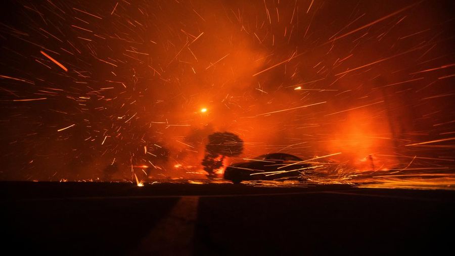 Sebuah mobil melaju melewati bara api yang diterpa angin saat Kebakaran Palisades berkobar selama badai angin di sisi barat Los Angeles, California, AS, 7 Januari 2025. (REUTERS/Ringo Chiu)