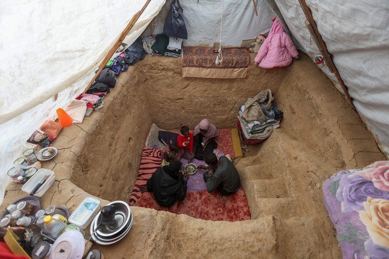 Warga Palestina Tayseer Obaid, bersama keluarganya duduk di dalam lubang bawah tanah yang digalinya untuk melindungi dari serangan Israel di perkemahan pengungsi Deir Al-Balah, Jalur Gaza bagian tengah, Senin (6/1/2025). (REUTERS/Ramadan Abed) Warga Palestina Tayseer Obaid, bersama keluarganya duduk di dalam lubang bawah tanah yang digalinya untuk melindungi dari serangan Israel di perkemahan pengungsi Deir Al-Balah, Jalur Gaza bagian tengah, Senin (6/1/2025). (REUTERS/Ramadan Abed)
