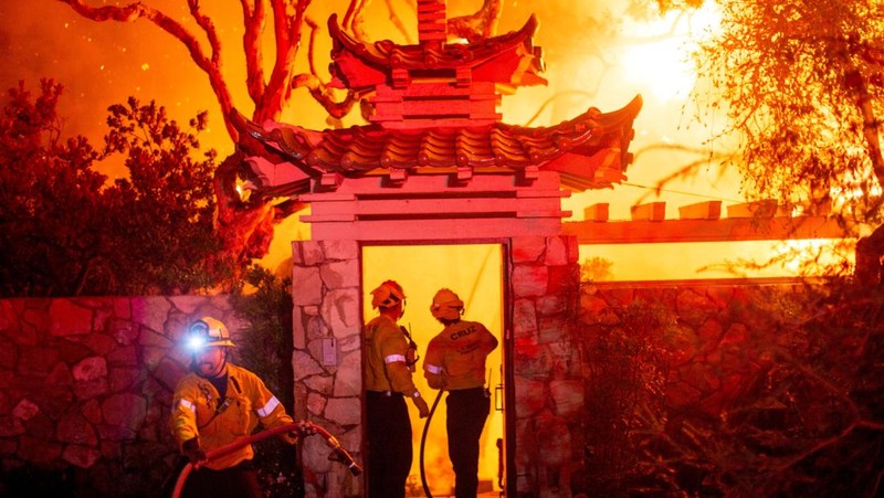 Helikopter menyemprotkan air ke lokasi kebakaran Sunset Fire di kawasan Hollywood Hills, Los Angeles, Rabu, 8 Januari 2025. (AP/Ethan Swope)