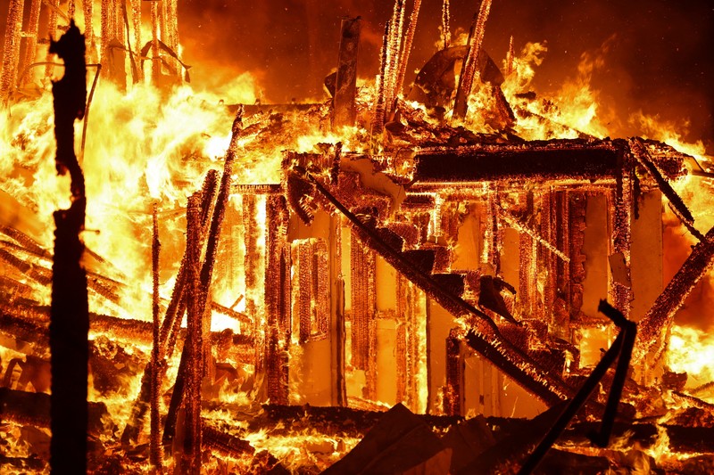 Seorang yang membawa bendera berjalan menjauh dari rumah yang terbakar saat angin kencang yang memicu kebakaran hutan yang dahsyat di wilayah Los Angeles memaksa orang-orang untuk mengungsi, di Kebakaran Eaton di Altadena, California, AS, 8 Januari 2025. (REUTERS/David Swanson) Seorang yang membawa bendera berjalan menjauh dari rumah yang terbakar saat angin kencang yang memicu kebakaran hutan yang dahsyat di wilayah Los Angeles memaksa orang-orang untuk mengungsi, di Kebakaran Eaton di Altadena, California, AS, 8 Januari 2025. (REUTERS/David Swanson)