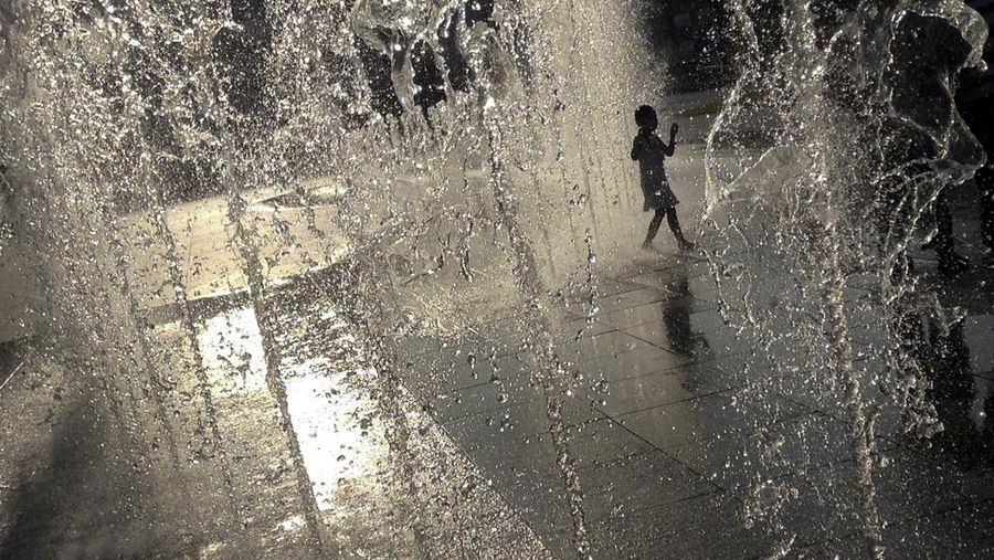 A child is silhouetted as she cools off from the heat in a water feature on Sunday, Sept. 29, 2013 at a local mall in Singapore during sunset. Singapore is well known for its hot and humid weather all year round.(AP Photo/Wong Maye-E)