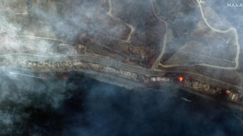 Seorang yang membawa bendera berjalan menjauh dari rumah yang terbakar saat angin kencang yang memicu kebakaran hutan yang dahsyat di wilayah Los Angeles memaksa orang-orang untuk mengungsi, di Kebakaran Eaton di Altadena, California, AS, 8 Januari 2025. (REUTERS/David Swanson)