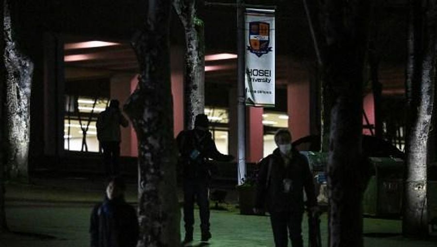 Orang-orang berjalan melewati spanduk Universitas Hosei di dekat pintu masuk kampus Tama universitas tersebut setelah seorang wanita melakukan serangan palu di dalam ruang kelas, di Machida di pinggiran barat Tokyo pada 10 Januari 2025. Delapan orang terluka dalam serangan palu di sebuah universitas di Tokyo pada 10 Januari, dengan seorang mahasiswa berusia 22 tahun ditangkap di tempat kejadian, kata media Jepang. (Foto oleh Philip FONG / AFP)