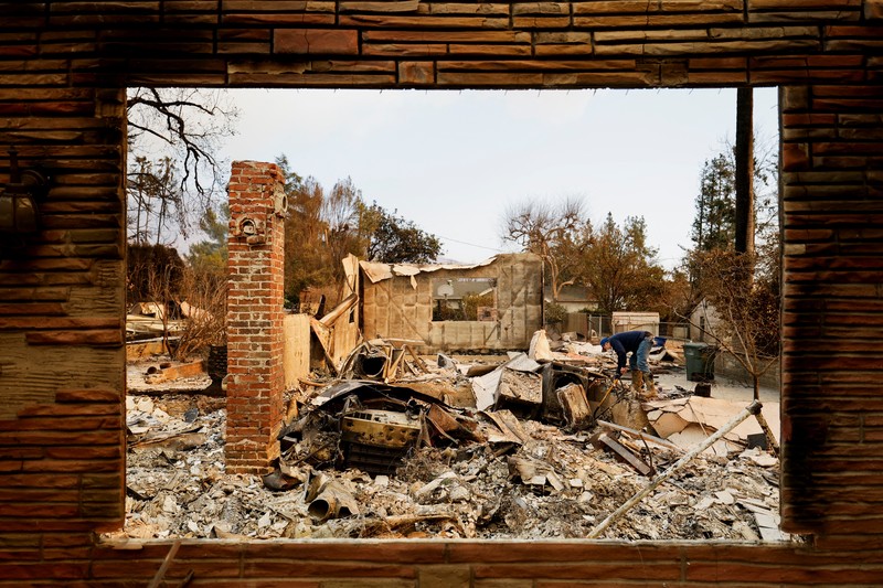 Seorang yang membawa bendera berjalan menjauh dari rumah yang terbakar saat angin kencang yang memicu kebakaran hutan yang dahsyat di wilayah Los Angeles memaksa orang-orang untuk mengungsi, di Kebakaran Eaton di Altadena, California, AS, 8 Januari 2025. (REUTERS/David Swanson) Seorang yang membawa bendera berjalan menjauh dari rumah yang terbakar saat angin kencang yang memicu kebakaran hutan yang dahsyat di wilayah Los Angeles memaksa orang-orang untuk mengungsi, di Kebakaran Eaton di Altadena, California, AS, 8 Januari 2025. (REUTERS/David Swanson)