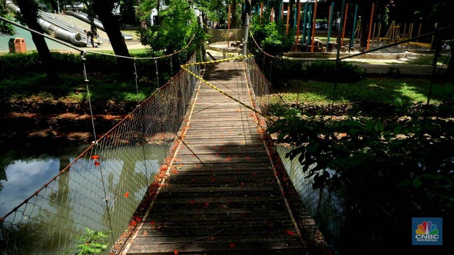 Pengunjung melintas disamping taman yang diberi pembatas di Kawasan Tebet Eco Park, Jakarta, Senin,(13/1/2025). Viral permainan Koin Jagat yang banyak diikuti remaja di Jakarta. Dinas Pertamanan dan Hutan (Distamhut) Kota Provinsi DKI Jakarta memasang pembatas. (CNBC Indonesia/Muhammad Sabki)