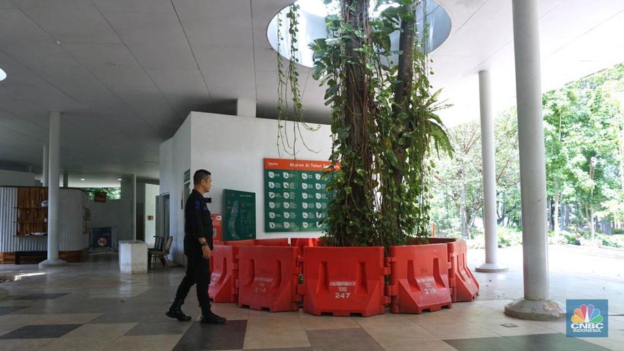 Pengunjung melintas disamping taman yang diberi pembatas di Kawasan Tebet Eco Park, Jakarta, Senin,(13/1/2025). Viral permainan Koin Jagat yang banyak diikuti remaja di Jakarta. Dinas Pertamanan dan Hutan (Distamhut) Kota Provinsi DKI Jakarta memasang pembatas. (CNBC Indonesia/Muhammad Sabki)