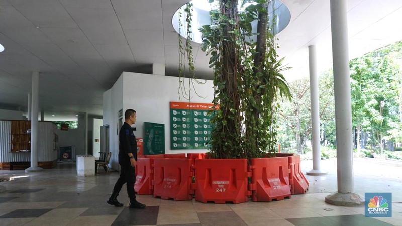 Pengunjung melintas disamping taman yang diberi pembatas di Kawasan Tebet Eco Park, Jakarta, Senin,(13/1/2025). Viral permainan Koin Jagat yang banyak diikuti remaja di Jakarta. Dinas Pertamanan dan Hutan (Distamhut) Kota Provinsi DKI Jakarta memasang pembatas. (CNBC Indonesia/Muhammad Sabki)