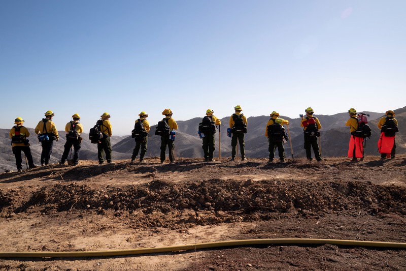 Petugas pemadam kebakaran dari Meksiko beristirahat sambil mendaki ke tujuan mereka untuk memotong garis penahanan di daerah Tarzana selama Kebakaran Palisades di Los Angeles, California, AS, 13 Januari 2025. Petugas pemadam kebakaran dari Meksiko beristirahat sambil mendaki ke tujuan mereka untuk memotong garis penahanan di daerah Tarzana selama Kebakaran Palisades di Los Angeles, California, AS, 13 Januari 2025. (REUTERS/David Ryder)