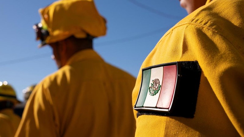 Petugas pemadam kebakaran dari Meksiko beristirahat sambil mendaki ke tujuan mereka untuk memotong garis penahanan di daerah Tarzana selama Kebakaran Palisades di Los Angeles, California, AS, 13 Januari 2025. (REUTERS/David Ryder)