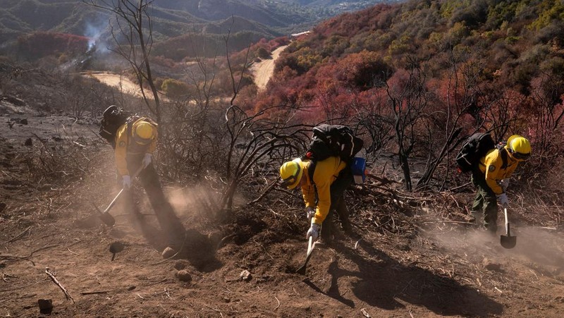 Petugas pemadam kebakaran dari Meksiko beristirahat sambil mendaki ke tujuan mereka untuk memotong garis penahanan di daerah Tarzana selama Kebakaran Palisades di Los Angeles, California, AS, 13 Januari 2025. (REUTERS/David Ryder)