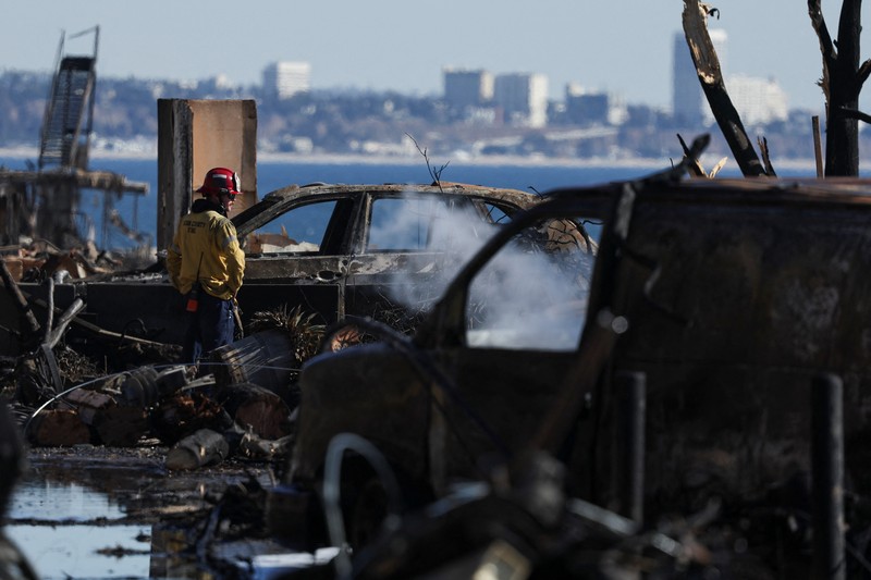 Sisa-sisa mobil rumah yang terbakar tergeletak di tanah, setelah angin kencang yang memicu kebakaran hutan yang dahsyat di wilayah Los Angeles memaksa orang-orang untuk mengungsi, di lingkungan Pacific Palisades di sisi barat Los Angeles, California, AS, 13 Januari 2025. (REUTERS/Daniel Cole)