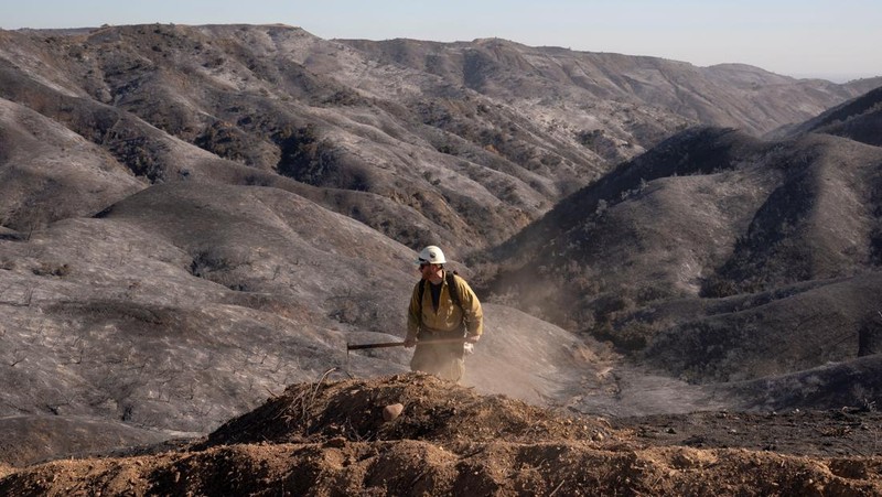 Petugas pemadam kebakaran dari Meksiko beristirahat sambil mendaki ke tujuan mereka untuk memotong garis penahanan di daerah Tarzana selama Kebakaran Palisades di Los Angeles, California, AS, 13 Januari 2025. (REUTERS/David Ryder)