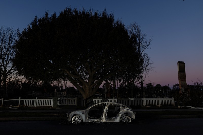Sisa-sisa mobil rumah yang terbakar tergeletak di tanah, setelah angin kencang yang memicu kebakaran hutan yang dahsyat di wilayah Los Angeles memaksa orang-orang untuk mengungsi, di lingkungan Pacific Palisades di sisi barat Los Angeles, California, AS, 13 Januari 2025. (REUTERS/Daniel Cole)