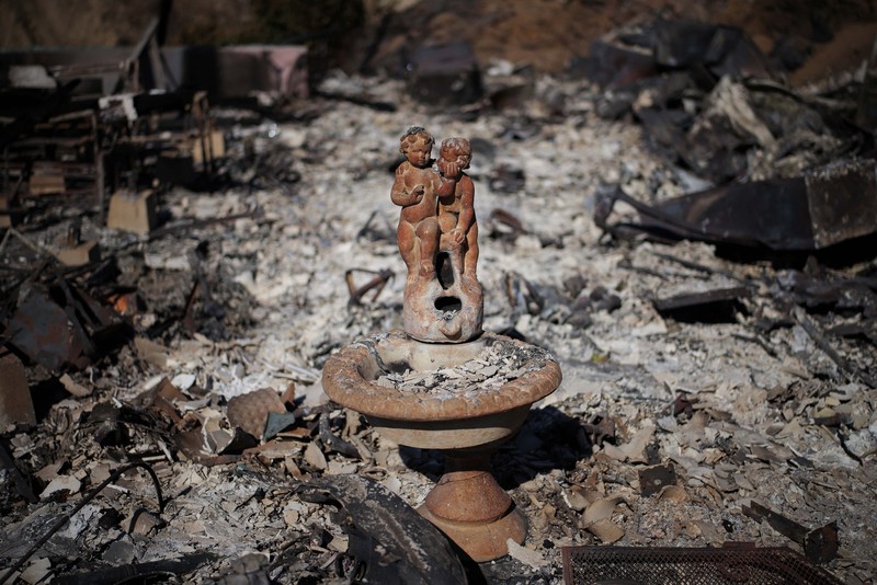 Sisa-sisa mobil rumah yang terbakar tergeletak di tanah, setelah angin kencang yang memicu kebakaran hutan yang dahsyat di wilayah Los Angeles memaksa orang-orang untuk mengungsi, di lingkungan Pacific Palisades di sisi barat Los Angeles, California, AS, 13 Januari 2025. (REUTERS/Daniel Cole)