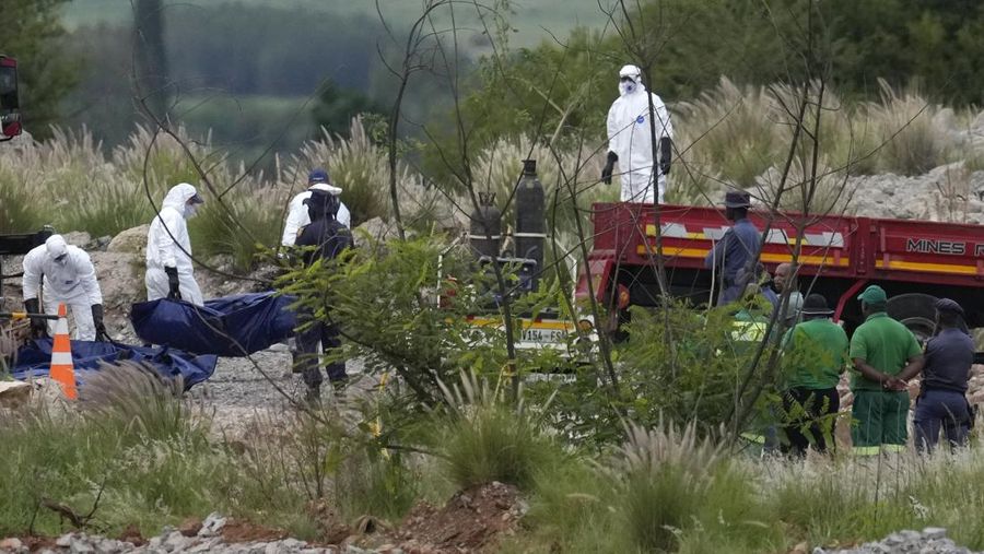 Petugas forensik membawa jenazah dalam kantong jenazah biru selama operasi penyelamatan para penambang dari bawah tanah di tambang emas terbengkalai di Stilfontein, Afrika Selatan, Selasa, 14 Januari 2025. (AP Photo/Themba Hadebe)