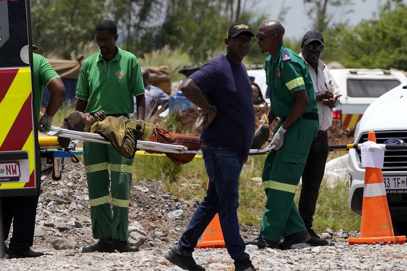 Petugas forensik membawa jenazah dalam kantong jenazah biru selama operasi penyelamatan para penambang dari bawah tanah di tambang emas terbengkalai di Stilfontein, Afrika Selatan, Selasa, 14 Januari 2025. (AP Photo/Themba Hadebe)